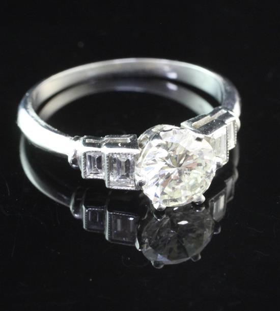 A platinum and single stone diamond ring with graduated emerald cut diamond set shoulders, size N.